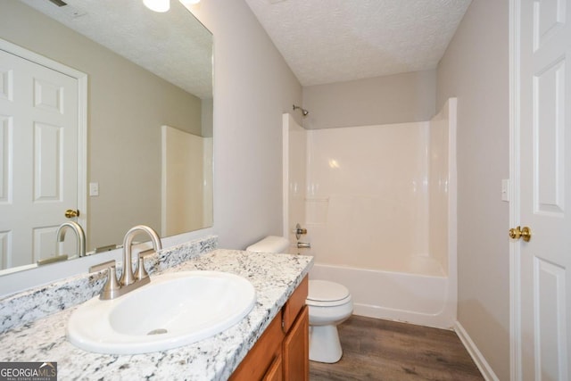 full bathroom with bathtub / shower combination, wood-type flooring, a textured ceiling, vanity, and toilet