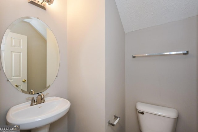 bathroom with a textured ceiling, toilet, and sink