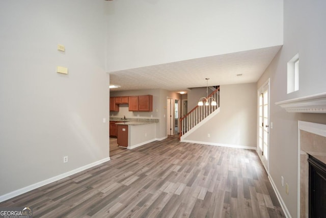 unfurnished living room with sink, a high end fireplace, a textured ceiling, a chandelier, and hardwood / wood-style flooring