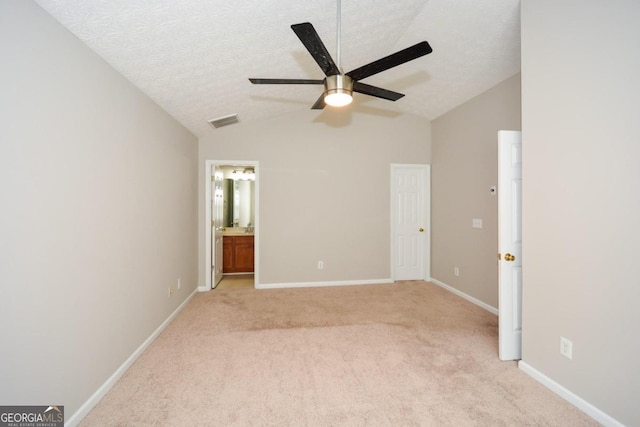 unfurnished bedroom with lofted ceiling, ceiling fan, ensuite bathroom, and a textured ceiling