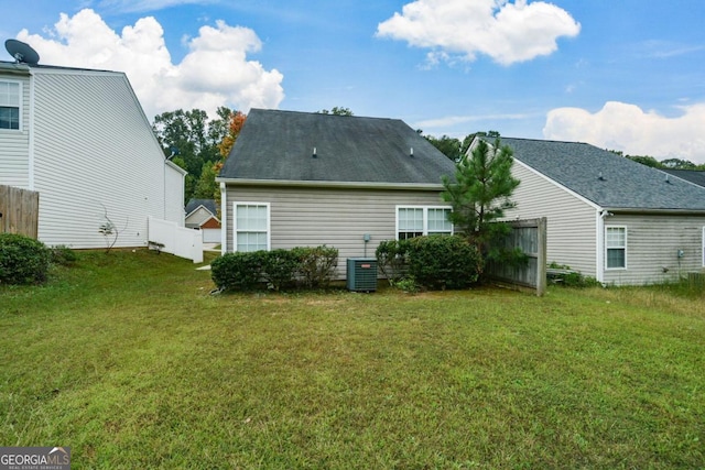 rear view of property with a yard and central air condition unit