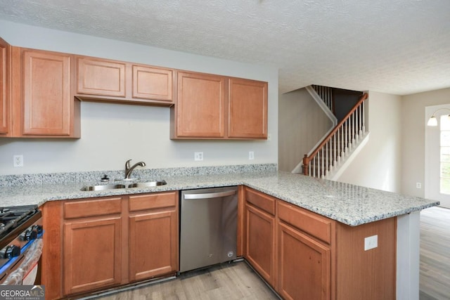 kitchen with sink, kitchen peninsula, light hardwood / wood-style flooring, appliances with stainless steel finishes, and light stone countertops