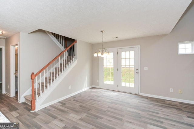 interior space with a textured ceiling, wood-type flooring, and a notable chandelier