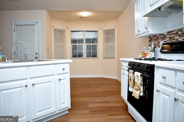 kitchen featuring exhaust hood, a textured ceiling, white gas range, and white cabinetry