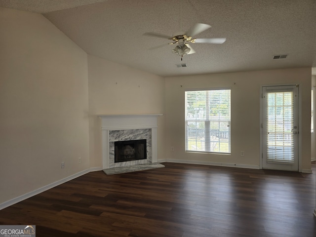 unfurnished living room featuring ceiling fan, a textured ceiling, a premium fireplace, dark hardwood / wood-style floors, and vaulted ceiling