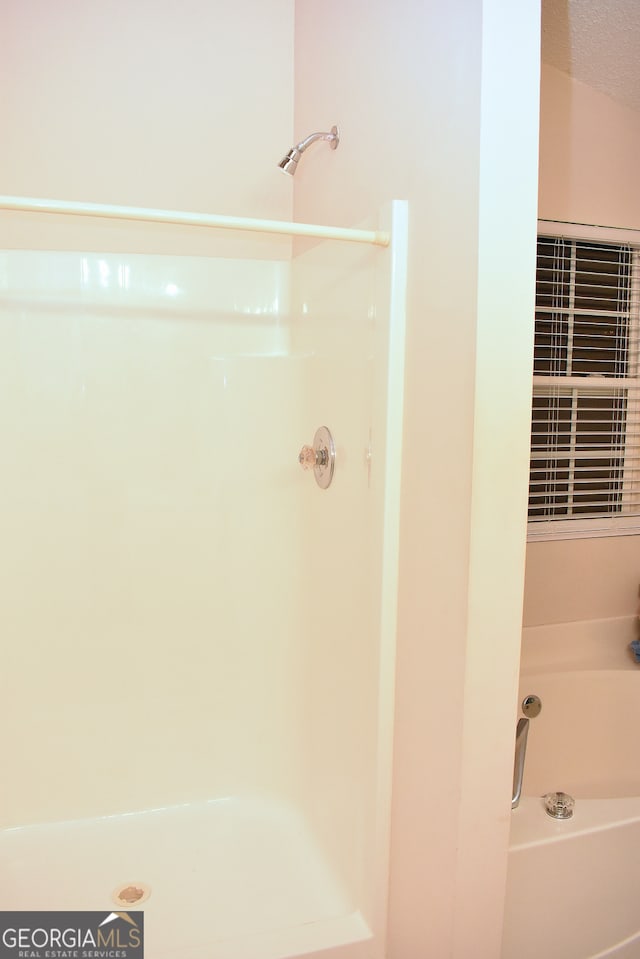 bathroom featuring a textured ceiling and independent shower and bath