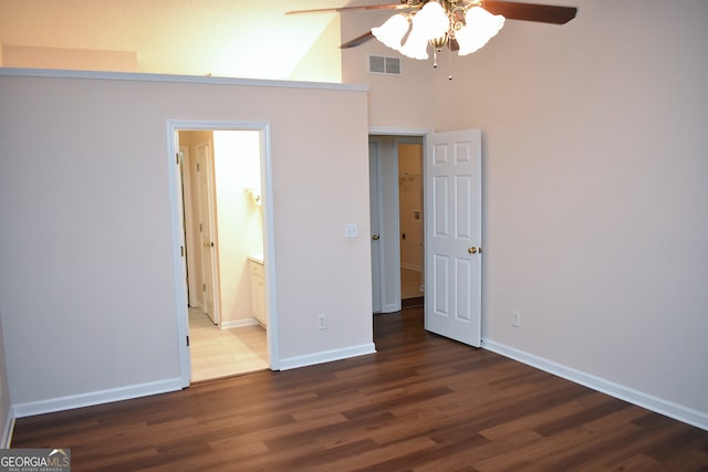 unfurnished bedroom featuring ceiling fan, ensuite bathroom, dark hardwood / wood-style flooring, and high vaulted ceiling