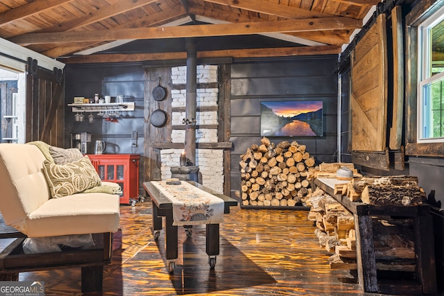 living area with vaulted ceiling with beams, a barn door, dark hardwood / wood-style floors, and wood ceiling