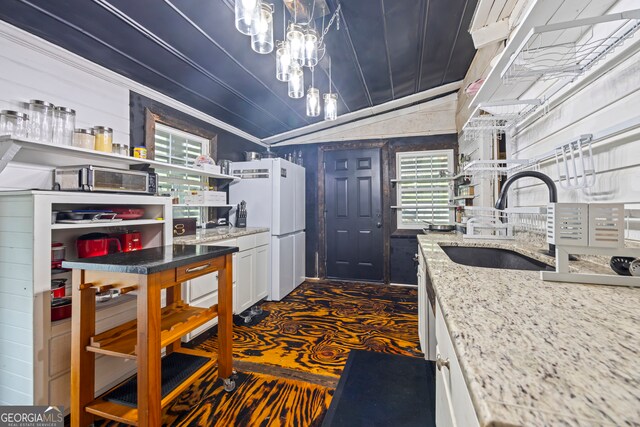 kitchen featuring dark colored carpet, sink, white fridge, light stone counters, and white cabinetry