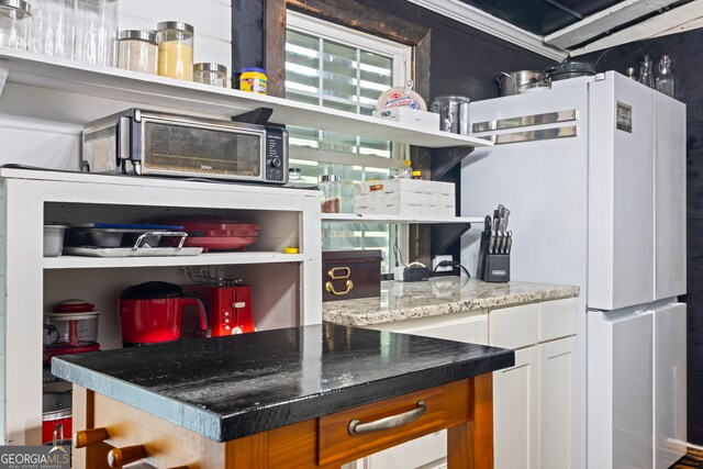 bar featuring white refrigerator, stone countertops, and white cabinetry