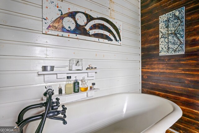 bathroom with a tub to relax in and wood walls