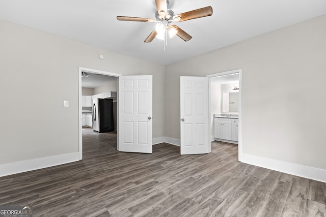 unfurnished bedroom featuring stainless steel fridge, ensuite bath, ceiling fan, and dark hardwood / wood-style flooring