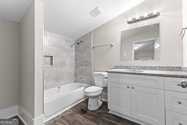 full bathroom featuring lofted ceiling, hardwood / wood-style floors, vanity, tiled shower / bath, and toilet