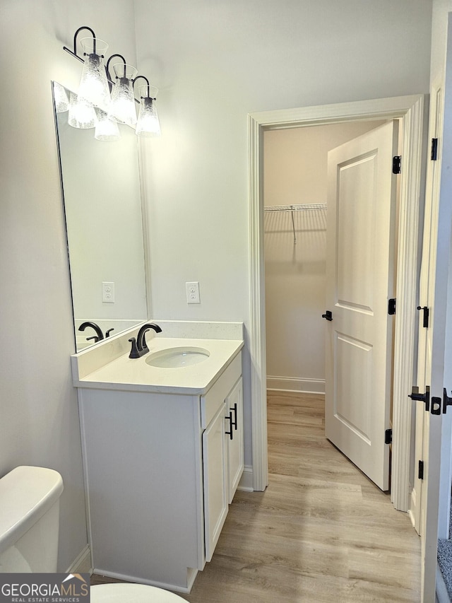 bathroom featuring toilet, wood-type flooring, and vanity