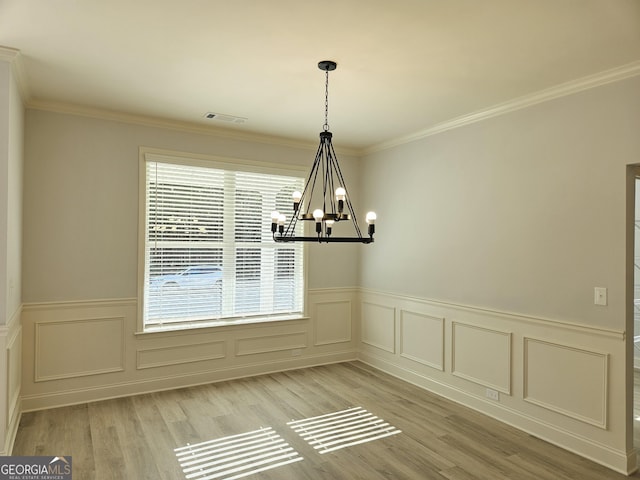 unfurnished dining area featuring an inviting chandelier, ornamental molding, and light hardwood / wood-style flooring