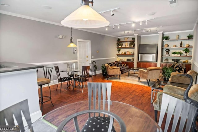 dining area with wood-type flooring, ornamental molding, and track lighting