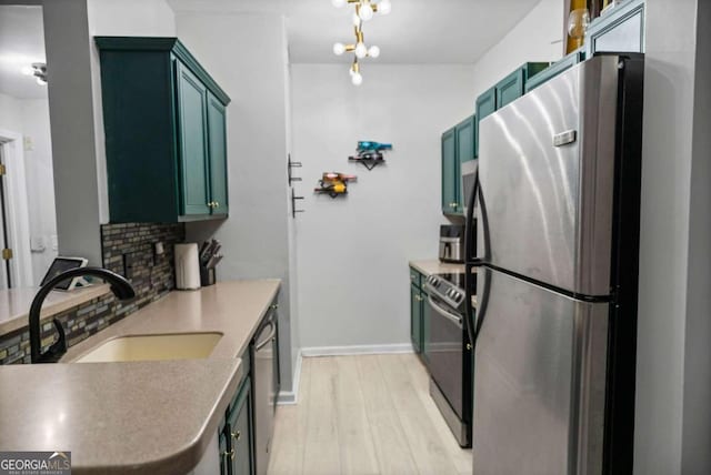 2700 Pine St NE Unit 2108, Atlanta, GA 30324 - kitchen featuring stainless steel appliances, a sink, green cabinetry, decorative backsplash, and light wood-style flooring