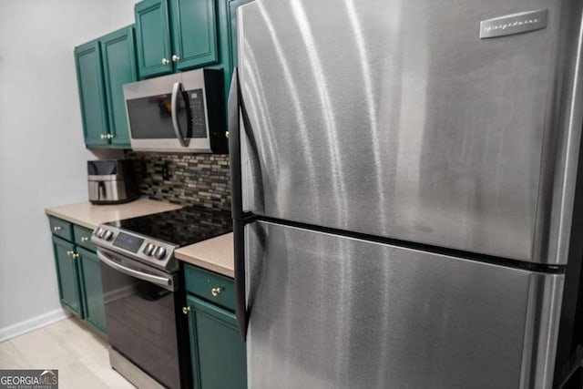 kitchen with appliances with stainless steel finishes, green cabinets, light hardwood / wood-style flooring, and tasteful backsplash