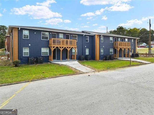 view of front of property featuring a balcony, central AC, and a front lawn