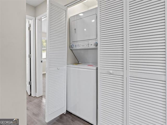 clothes washing area with dark hardwood / wood-style floors and stacked washer and clothes dryer