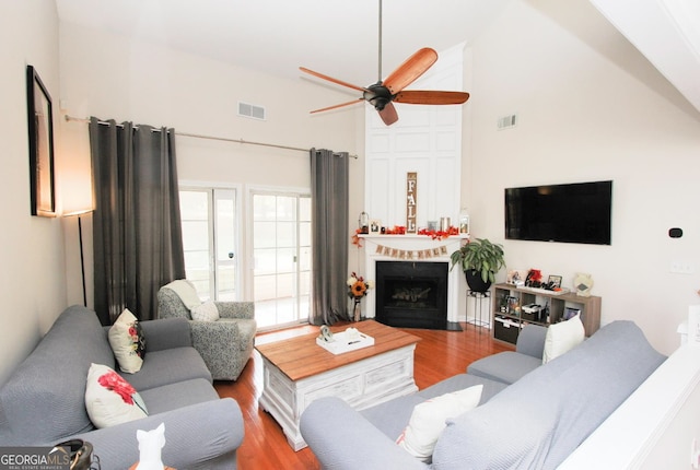 living room featuring ceiling fan, a towering ceiling, and hardwood / wood-style floors