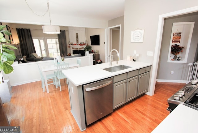 kitchen featuring pendant lighting, gray cabinets, light wood-type flooring, stainless steel dishwasher, and sink