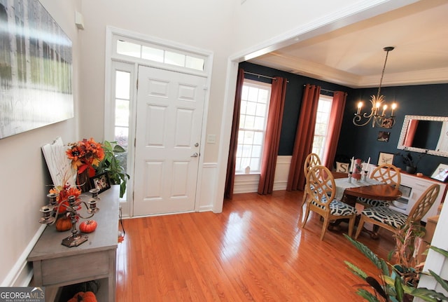 entryway featuring ornamental molding, wood-type flooring, and an inviting chandelier