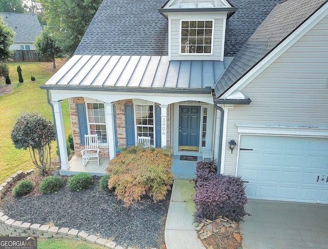 view of exterior entry with a lawn, a porch, and a garage