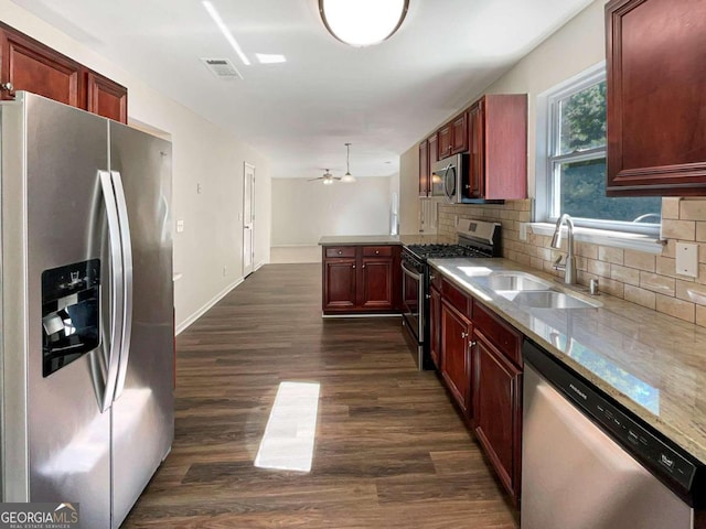 kitchen with tasteful backsplash, sink, hanging light fixtures, appliances with stainless steel finishes, and dark hardwood / wood-style flooring