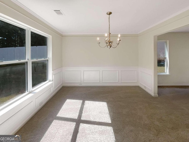 empty room featuring dark carpet, a chandelier, and crown molding