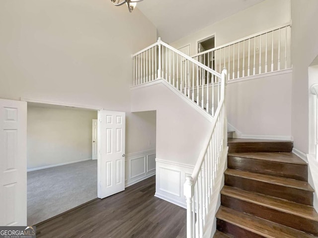 stairs with high vaulted ceiling and hardwood / wood-style floors