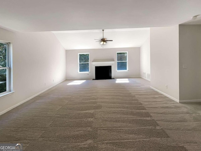 unfurnished living room with ceiling fan, lofted ceiling, and dark colored carpet