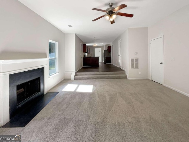 unfurnished living room with ceiling fan and dark colored carpet