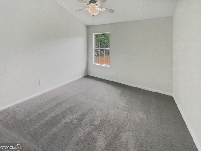 spare room featuring dark colored carpet and ceiling fan