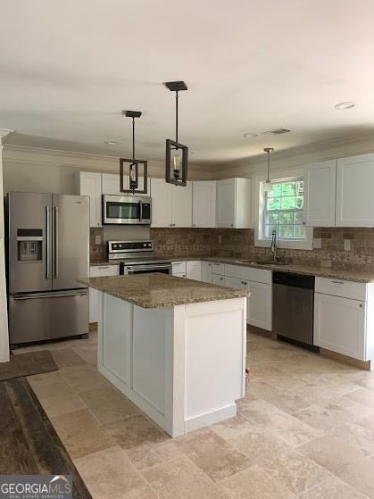 kitchen featuring stainless steel appliances, a kitchen island, sink, white cabinetry, and hanging light fixtures