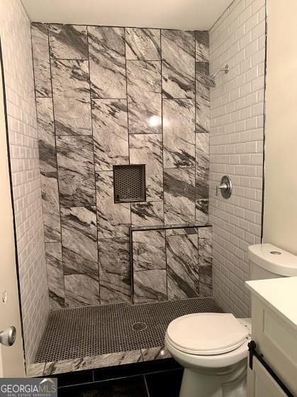 bathroom featuring vanity, toilet, tile patterned flooring, and tiled shower