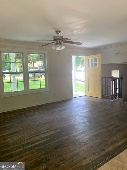 empty room featuring ornamental molding, a wealth of natural light, dark wood-type flooring, and ceiling fan