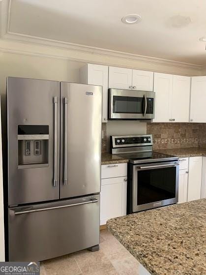 kitchen with stone counters, white cabinets, ornamental molding, tasteful backsplash, and stainless steel appliances