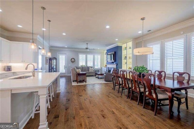 dining room featuring ceiling fan, ornamental molding, sink, and dark hardwood / wood-style flooring