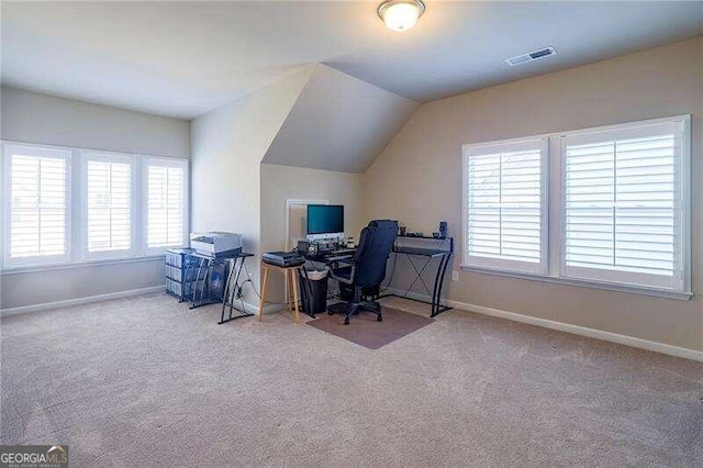 home office with lofted ceiling, light colored carpet, and a healthy amount of sunlight