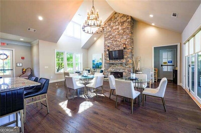 dining area with a stone fireplace, a chandelier, dark hardwood / wood-style flooring, and high vaulted ceiling