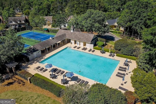 view of swimming pool with tennis court and a patio