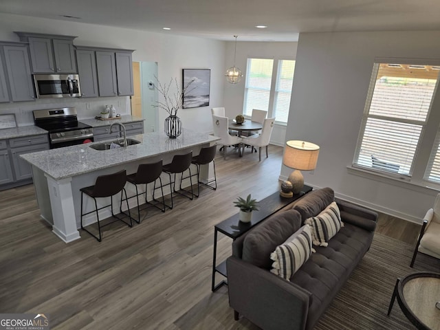 kitchen featuring appliances with stainless steel finishes, a breakfast bar, sink, hanging light fixtures, and a kitchen island with sink