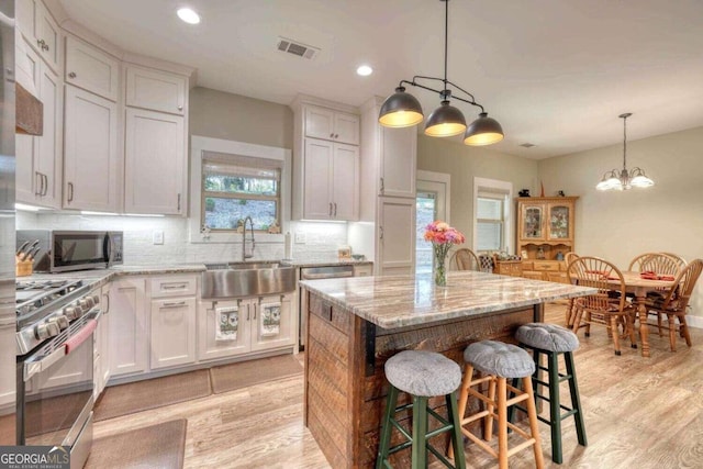 kitchen featuring white cabinetry, appliances with stainless steel finishes, a kitchen island, and sink