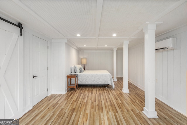 bedroom featuring light hardwood / wood-style floors, an AC wall unit, beam ceiling, a barn door, and wooden walls