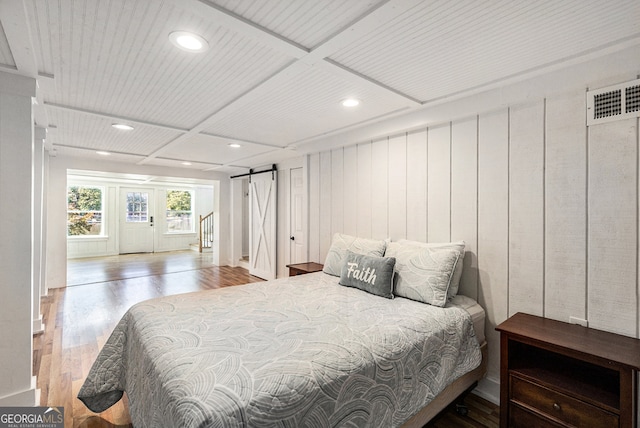 bedroom featuring a barn door and hardwood / wood-style floors