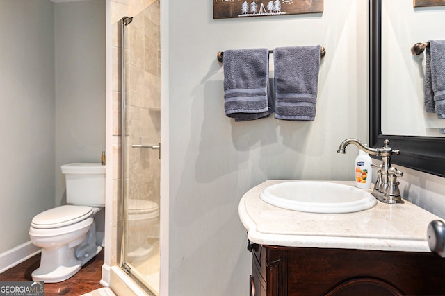 bathroom with vanity, a shower with shower door, toilet, and hardwood / wood-style flooring