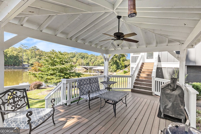 deck with a water view and ceiling fan