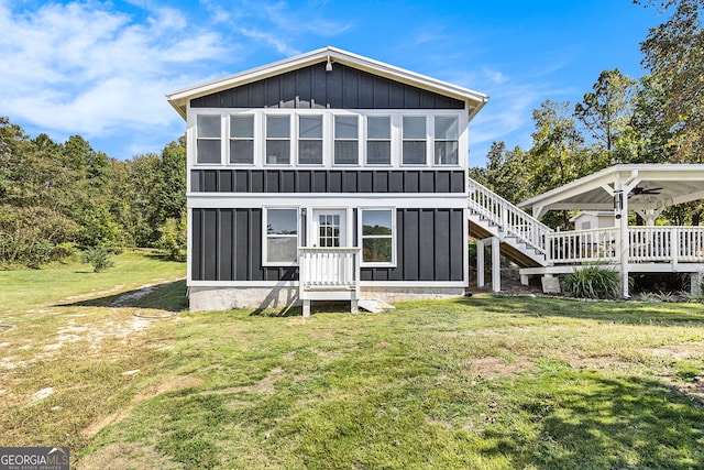 rear view of property featuring ceiling fan, a deck, and a yard