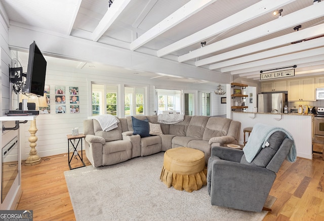 living room with light wood-type flooring, beamed ceiling, and wooden walls